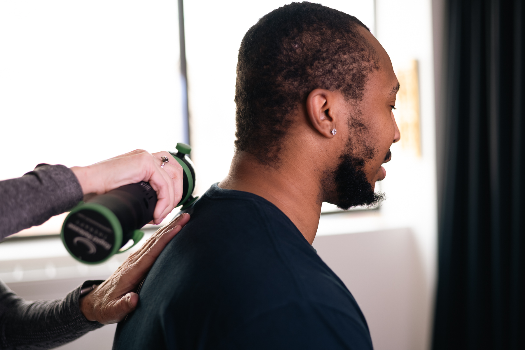 A Rapid Release Therapy device being used on a person's upper back and shoulder area