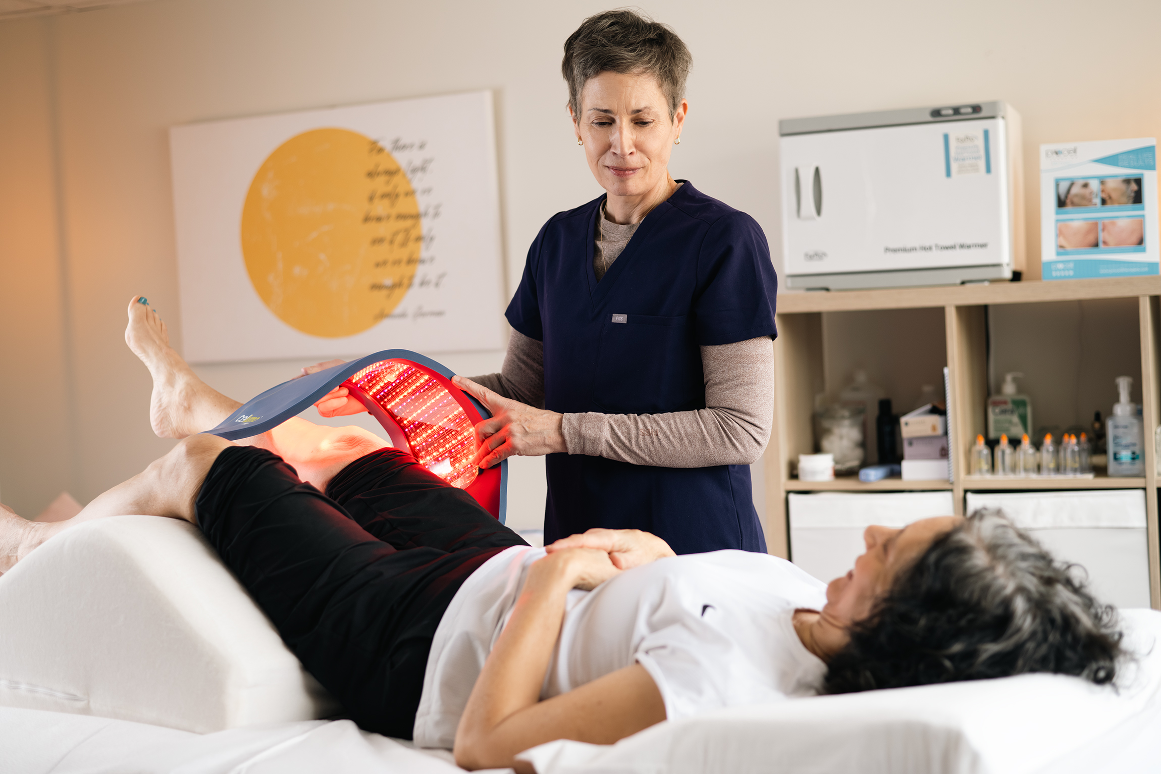 Practitioner using LED light therapy device for pain management treatment