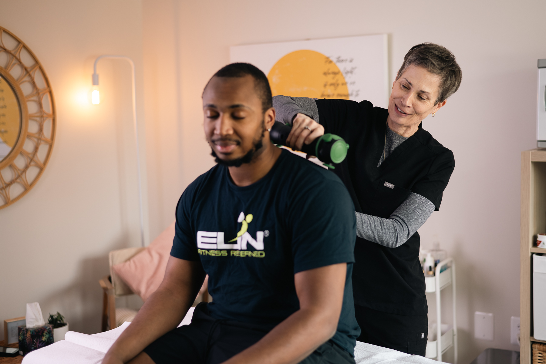 Practitioner using a Rapid Release therapy device on a seated man's back