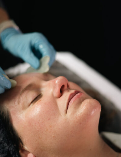 A facial gua sha treatment on a relaxed woman