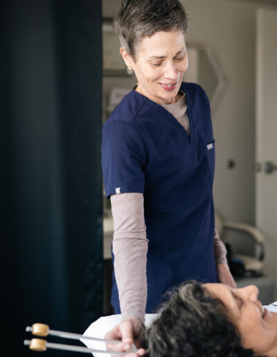 A practitioner using a tuning fork for sound therapy on a relaxed patient